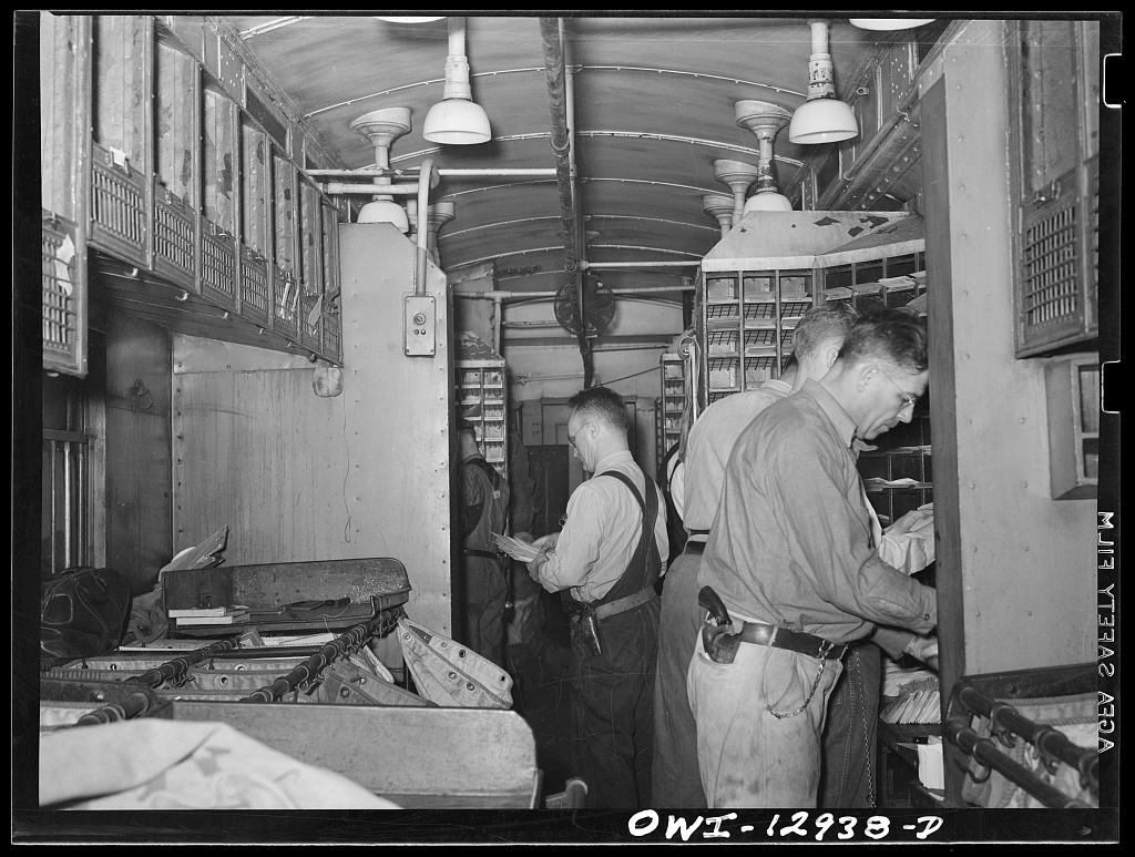 Public domain photograph of postal workers sorting mail in transit.